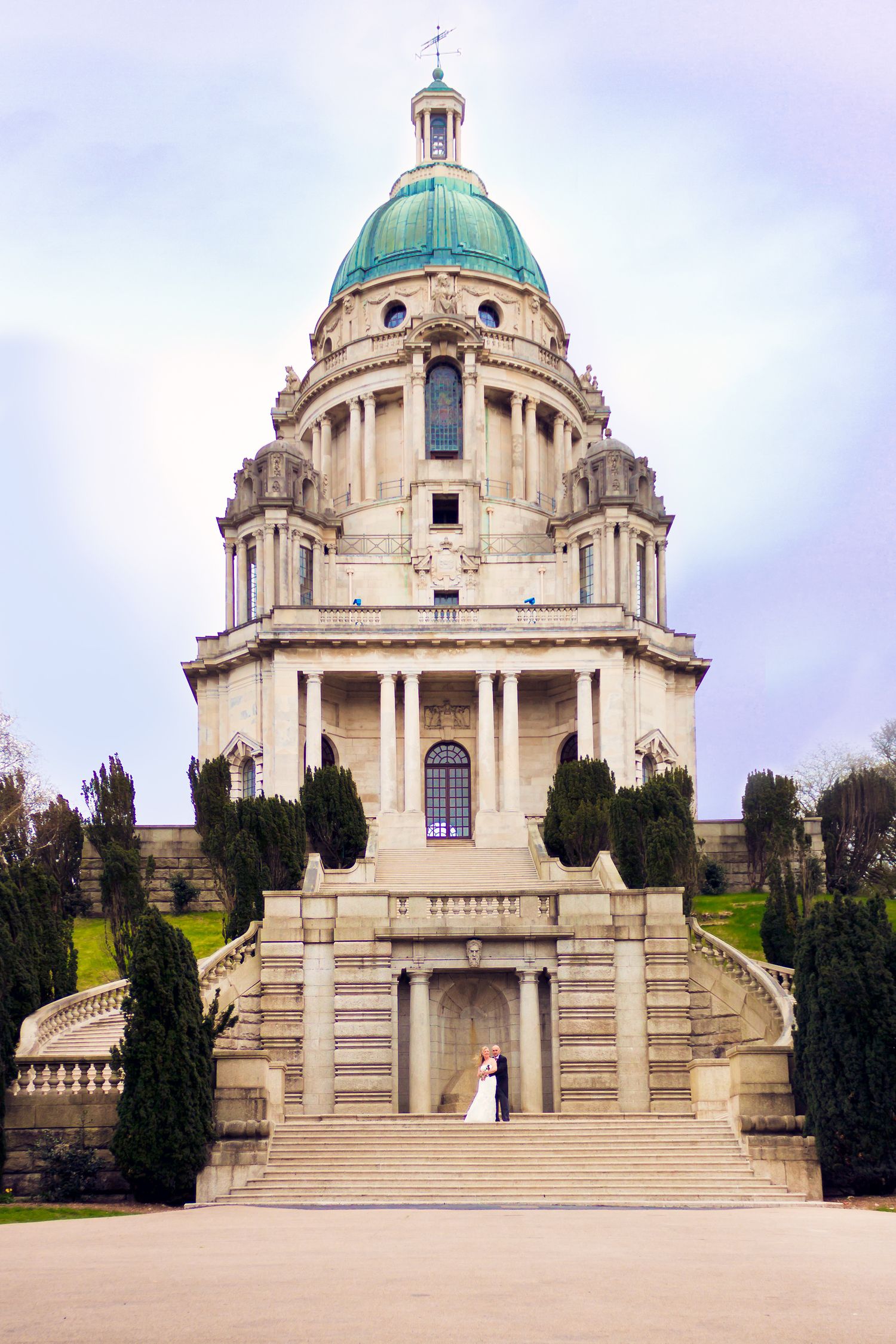 Majestic domed cathedral with neoclassical architecture and grand staircase under cloudy sky.