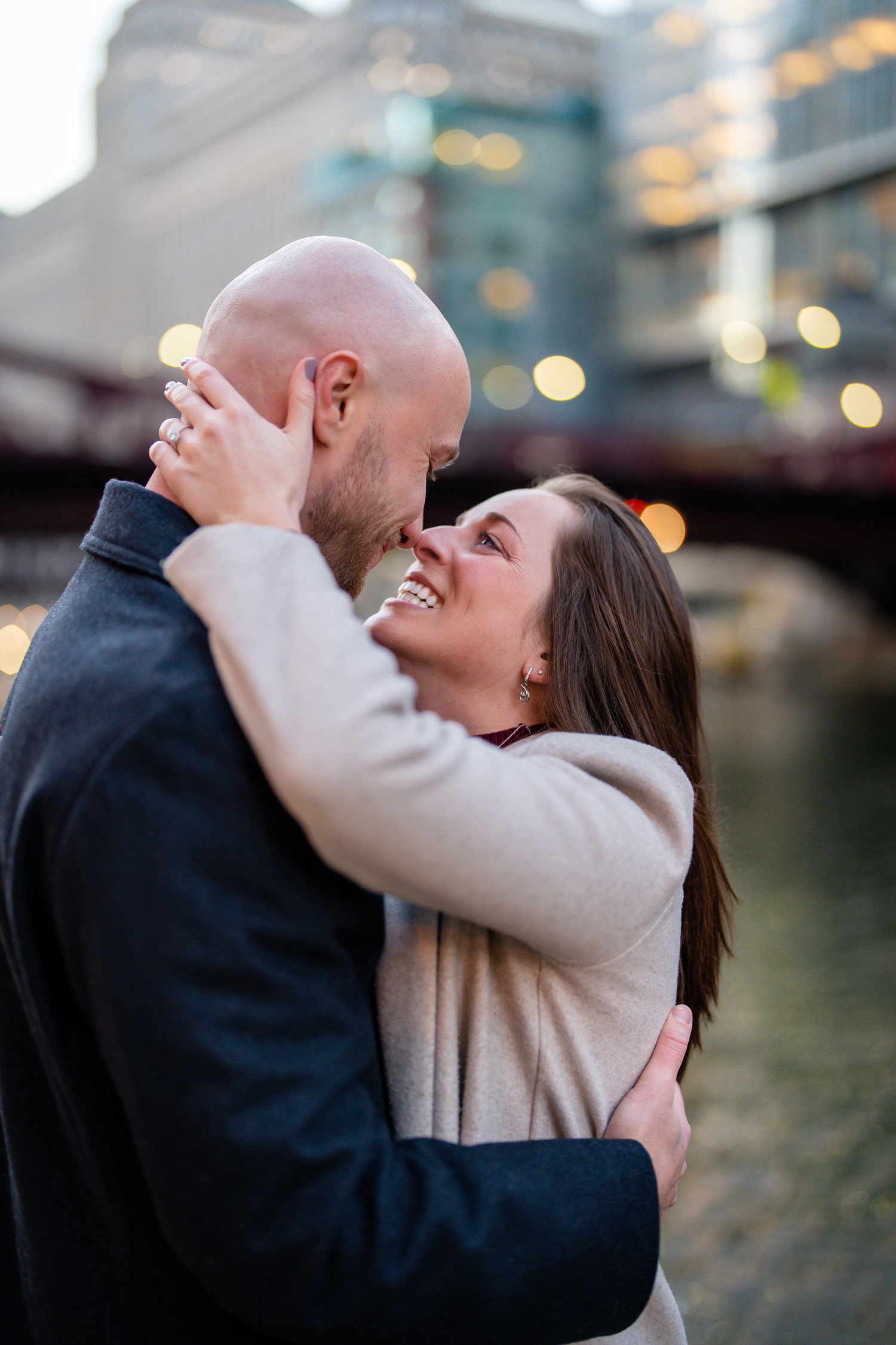 Romantic couple embracing and laughing during sunset in an urban setting.