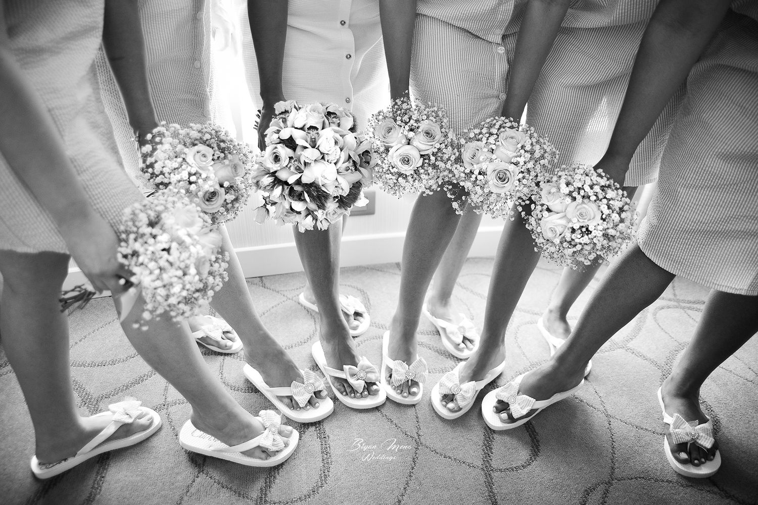 Wedding party members show off matching white flip flops and flowers in a circle formation.