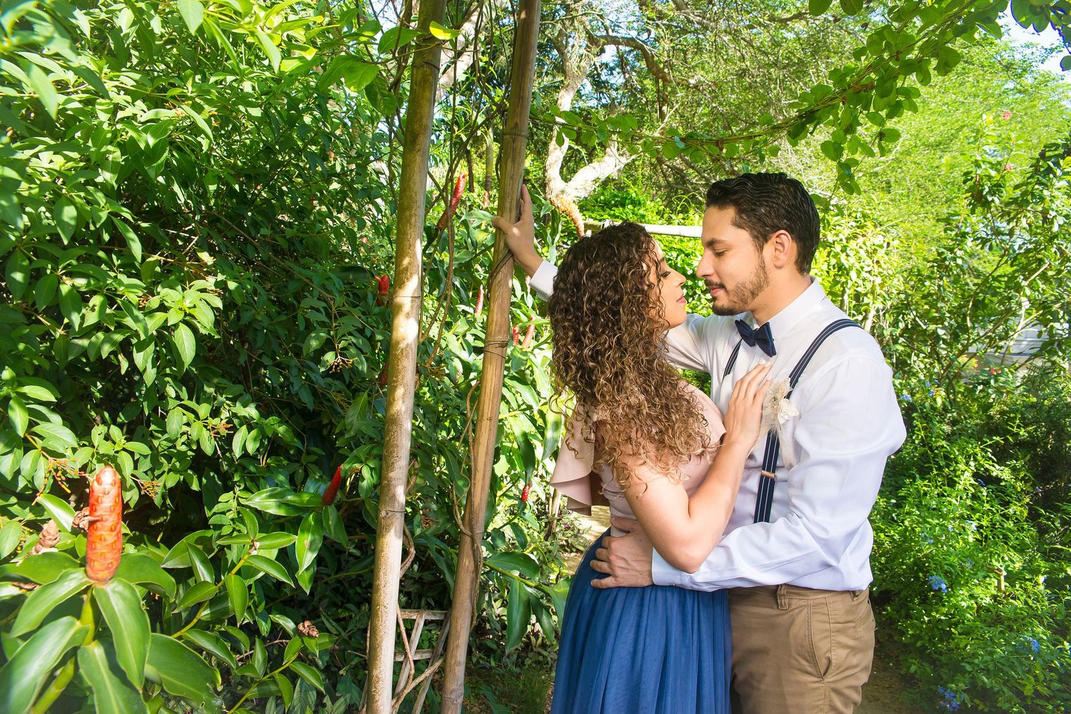 Couple embracing in lush garden setting with casual formal attire.