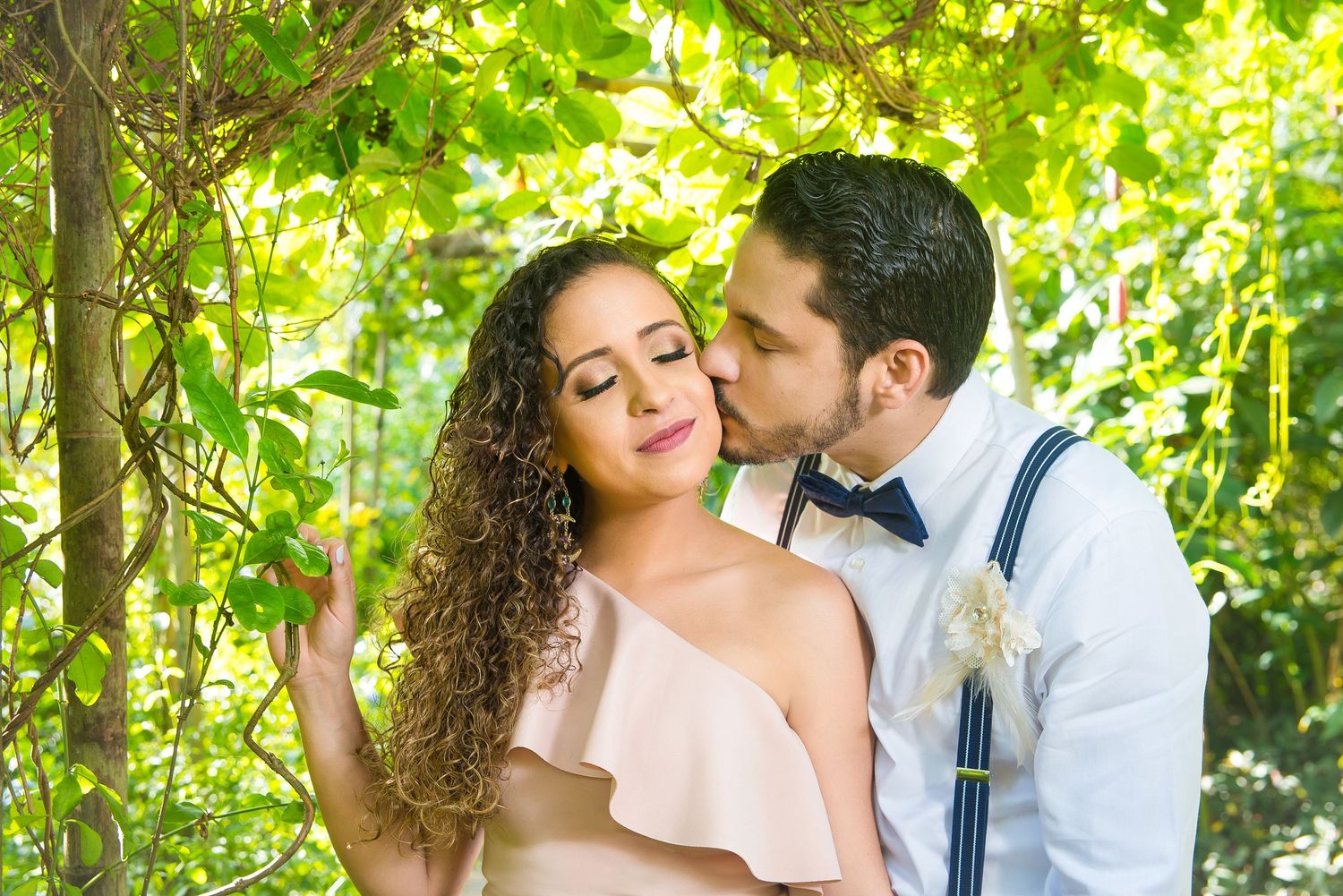 Romantic outdoor portrait under green foliage with suspenders and flowy dress.