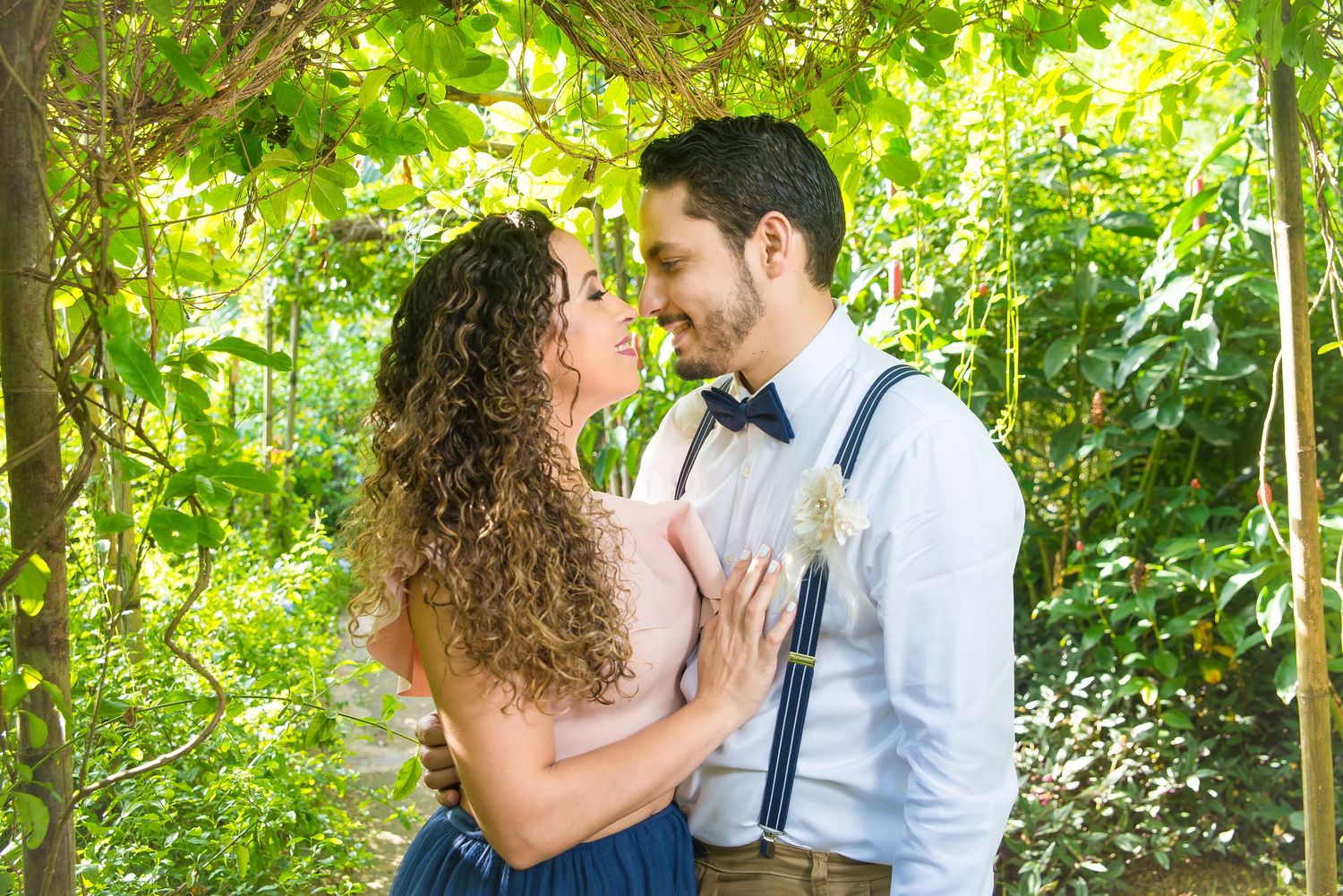 Couple sharing intimate moment under green garden archway.