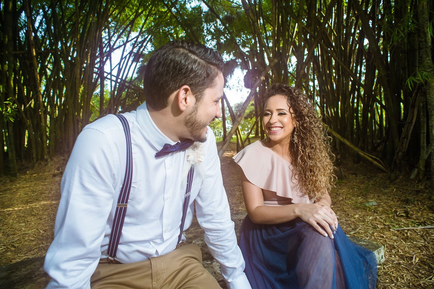 Couple laughing together while sitting in bamboo forest.