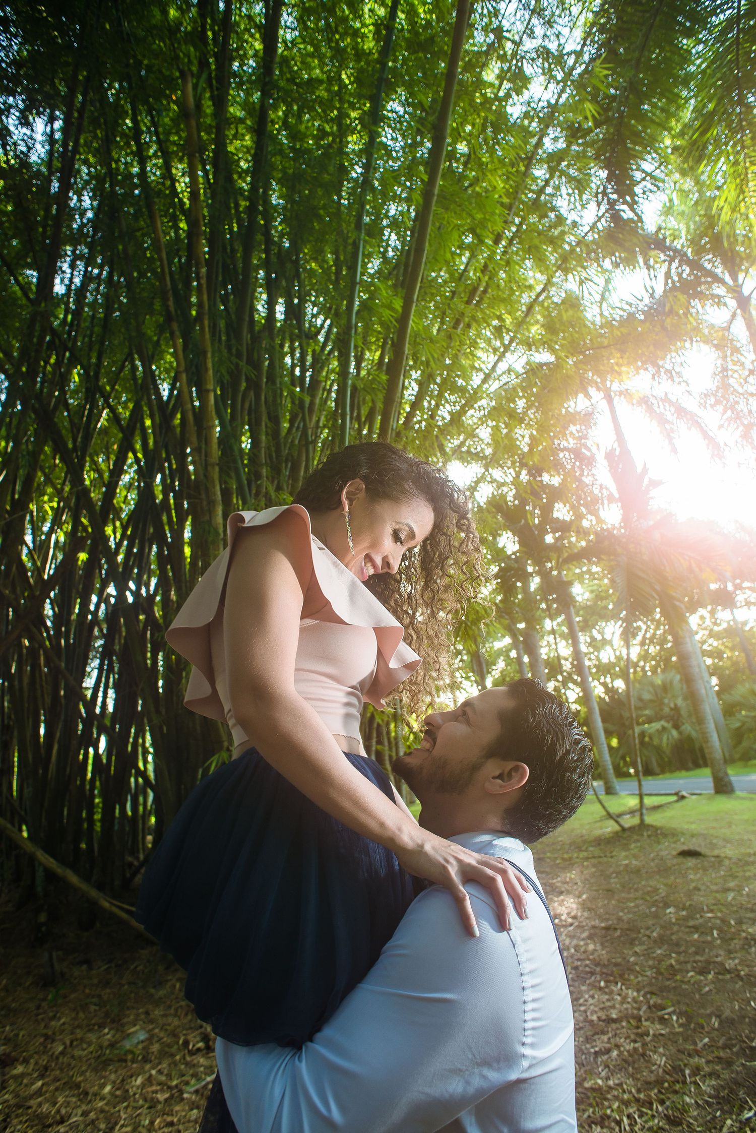 Romantic couple pose in sunlit bamboo garden.