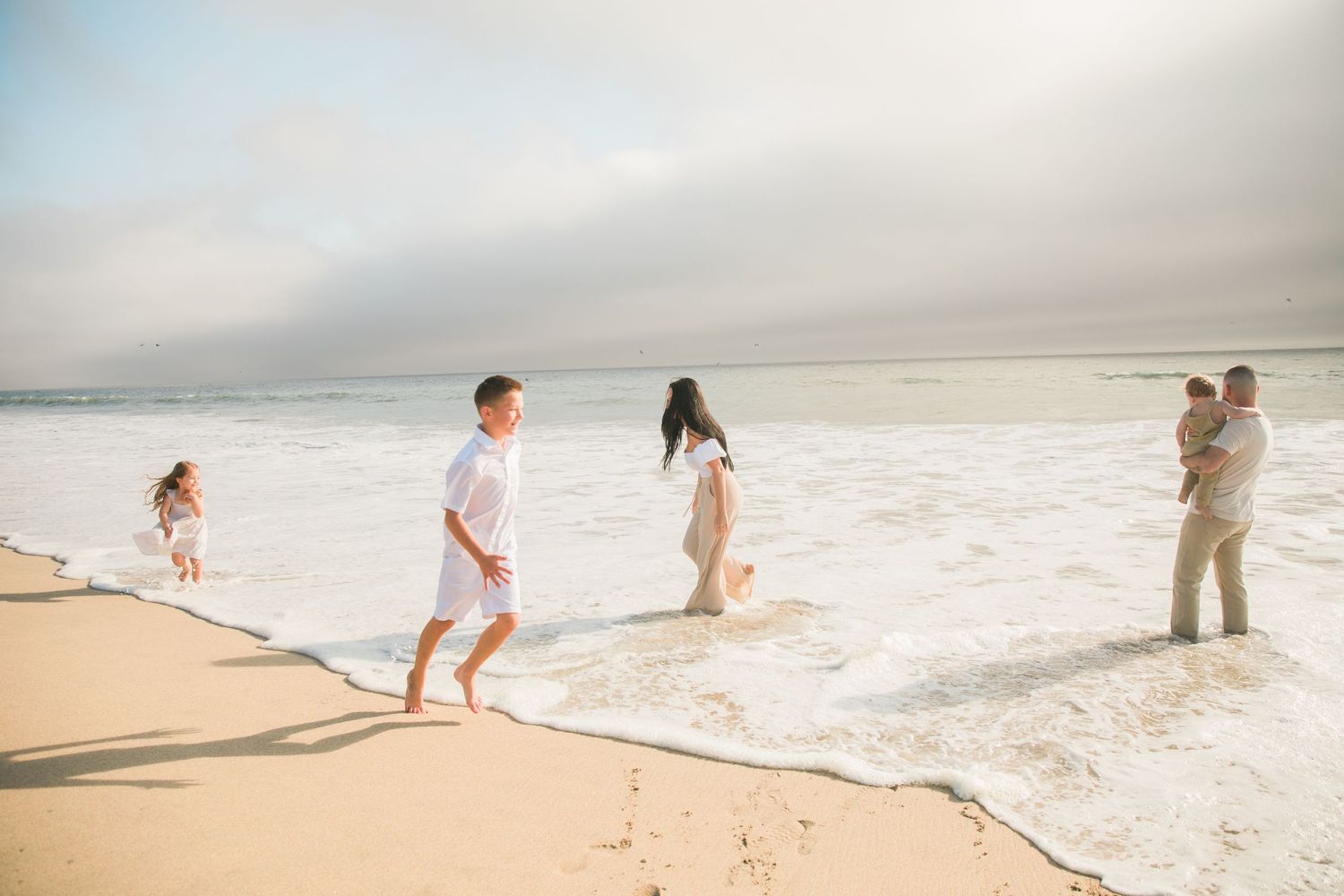 Family plays in the ocean waves in Half Moon Bay California.