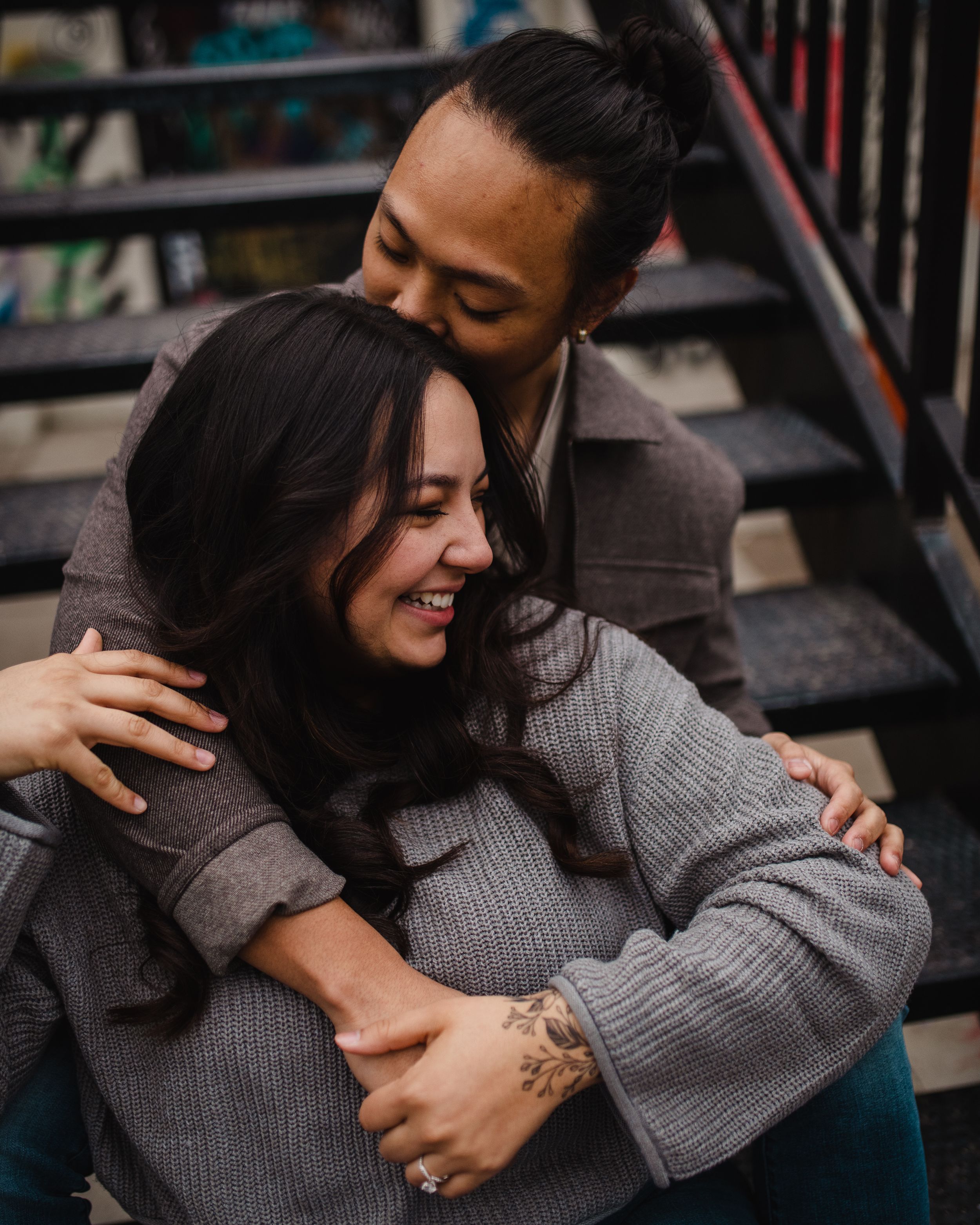 Intimate moment between couple wearing cozy sweaters during urban photoshoot.