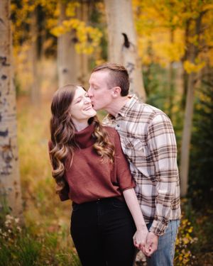 A couple shares a joyful moment among yellow autumn trees.