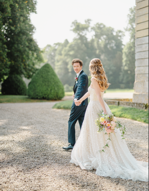 Wedding couple walking along a gravel path surrounded by lush greenery.