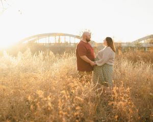 A romantic couple enjoys golden hour in a meadow with warm sunlit grass.