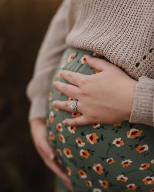 Close-up of hands showing engagement ring against a floral dress and sweater.