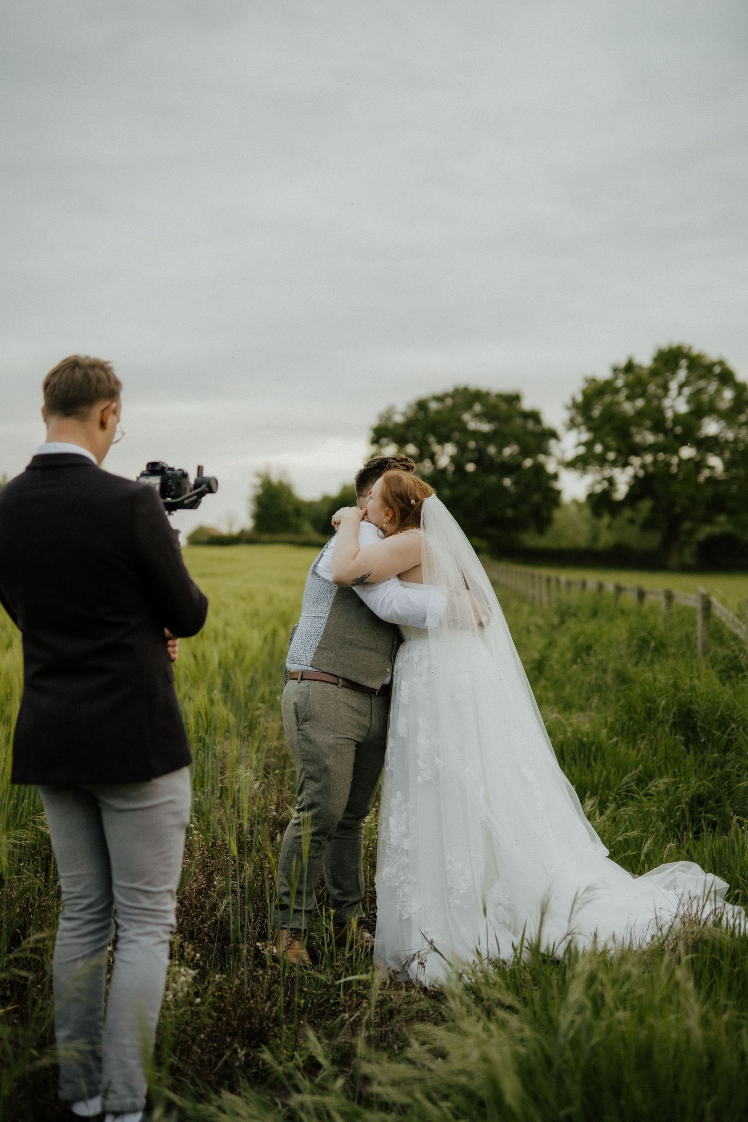Wedding photographer captures couple embracing in serene countryside setting.