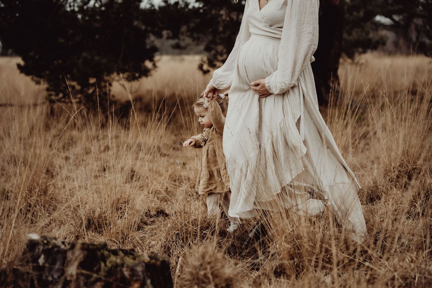 A flowing white dress catches the breeze in a golden field at sunset.