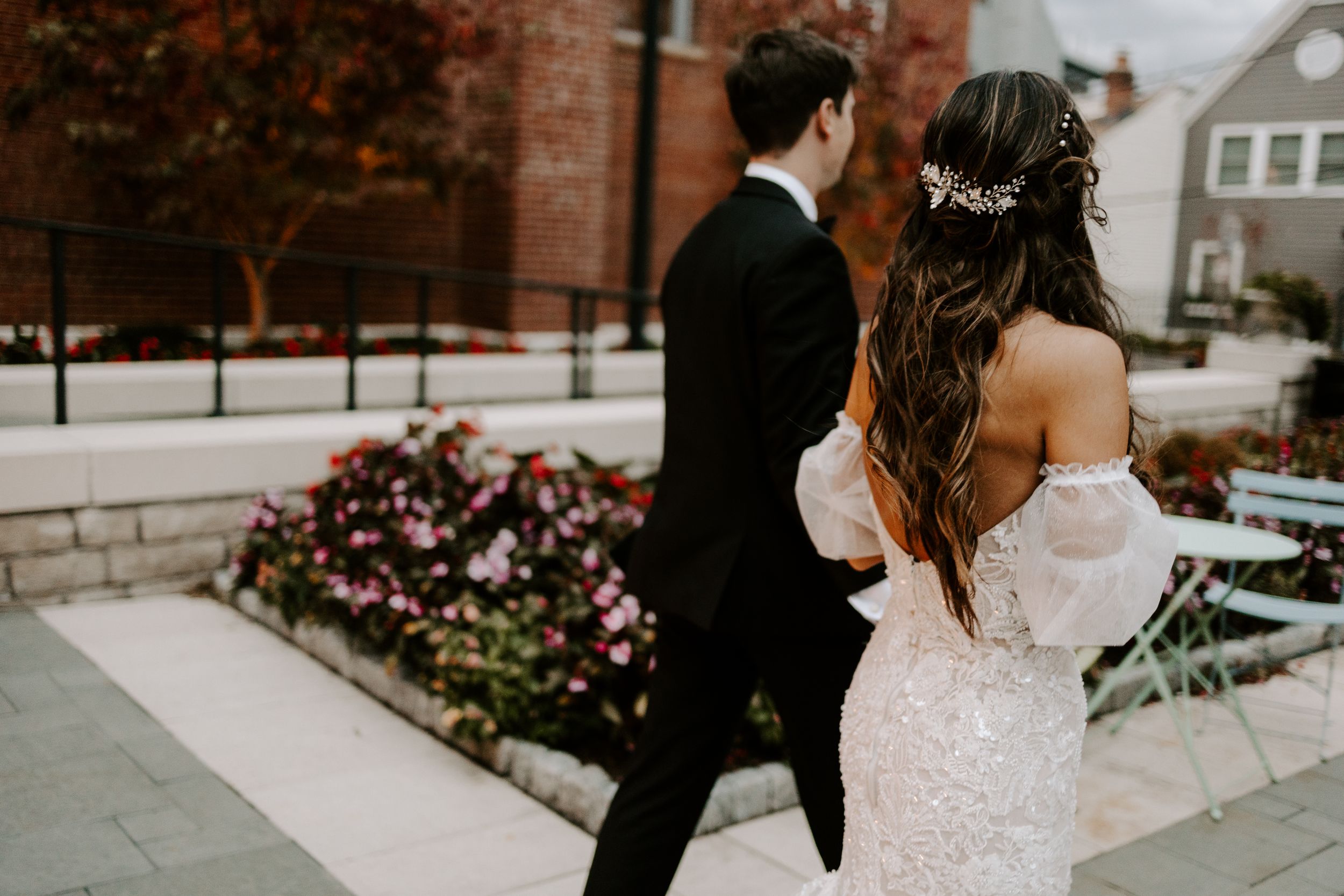 Wedding couple walking together on stone pathway near brick building.