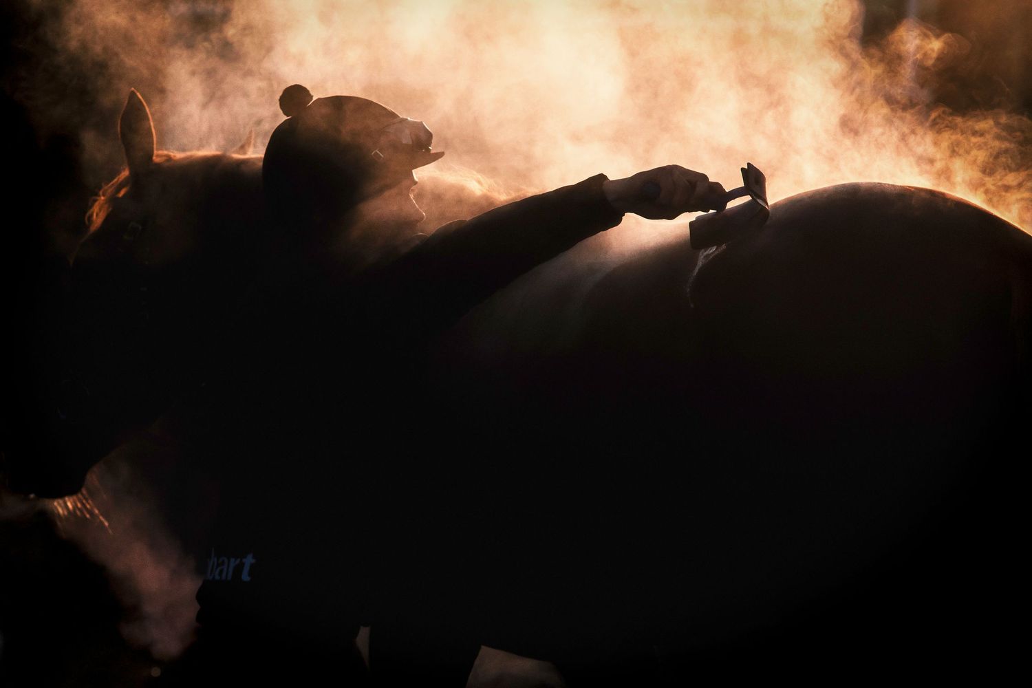 Silhouette of figures working with equipment against a fiery orange sky.