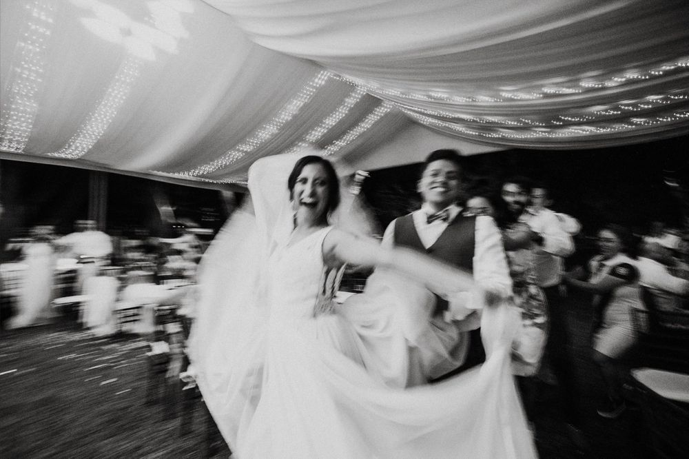 Multiple dance sequences at a wedding celebration shown in blurred motion on a dark background.