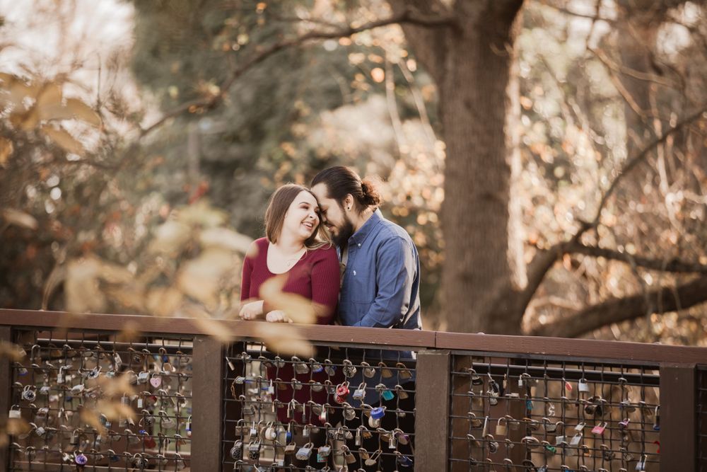 Couple shares intimate moment on rustic bridge during engagement shoot.