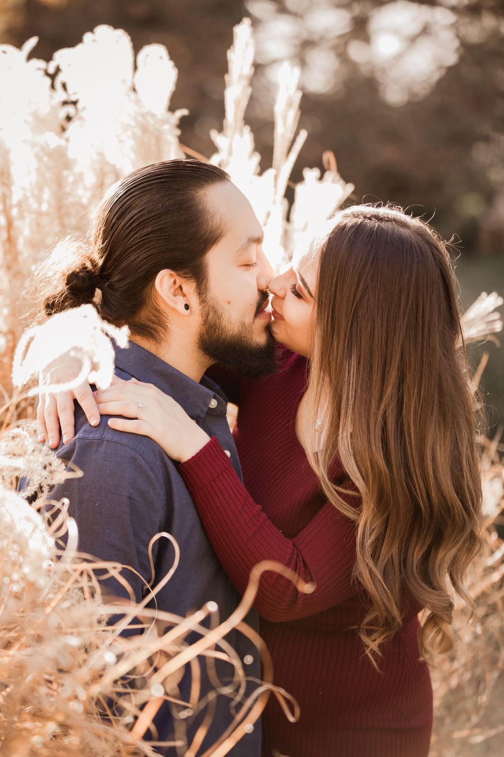Romantic couple kissing in golden sunlight among pampas grass.