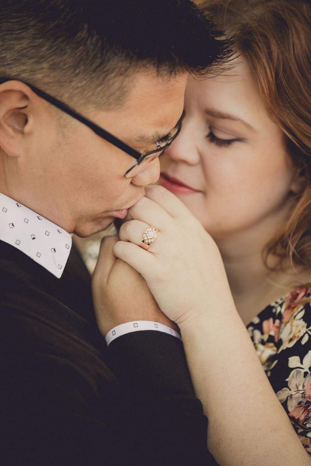 A romantic close-up of a tender moment showing an engagement ring and gentle embrace between two partners.