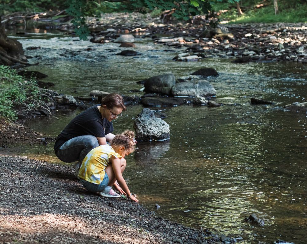 Parent and child exploring creek bed with rocks.