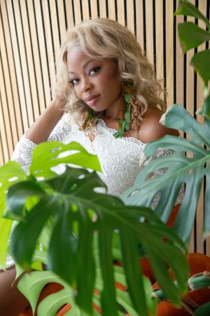 A tropical-themed portrait with monstera leaves and white lace against wooden slats.