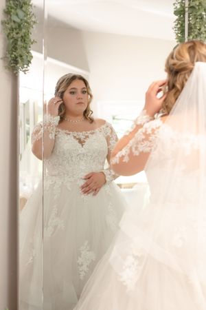 Bride-looking-at-her-reflection-in-a-mirror-before-the-ceremony-at-The-Barn-at-Higgins-Lake.