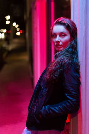 A-High-School-Senior-standing-under-pink-neon-lights-at-night-in-Midland-Michigan.