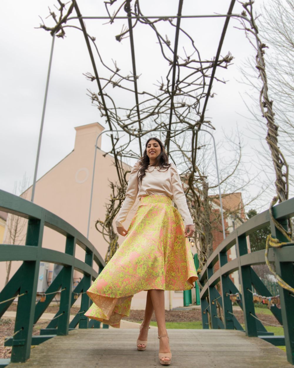 Stylish yellow midi skirt and white top ensemble photographed on wooden bridge.