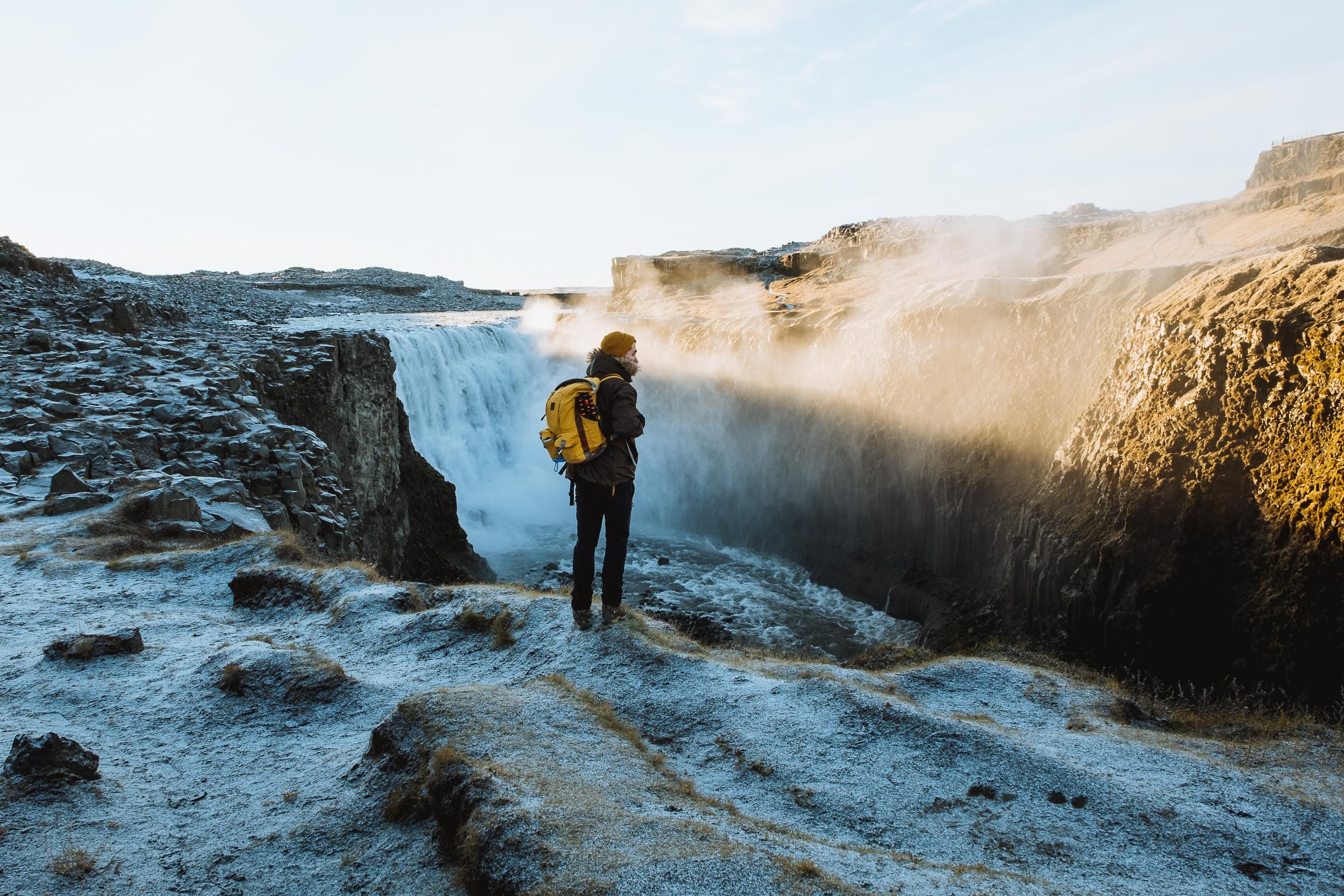 Scenic winter landscape with snow-covered cliffs and misty coastal views along a rugged shoreline at sunset.