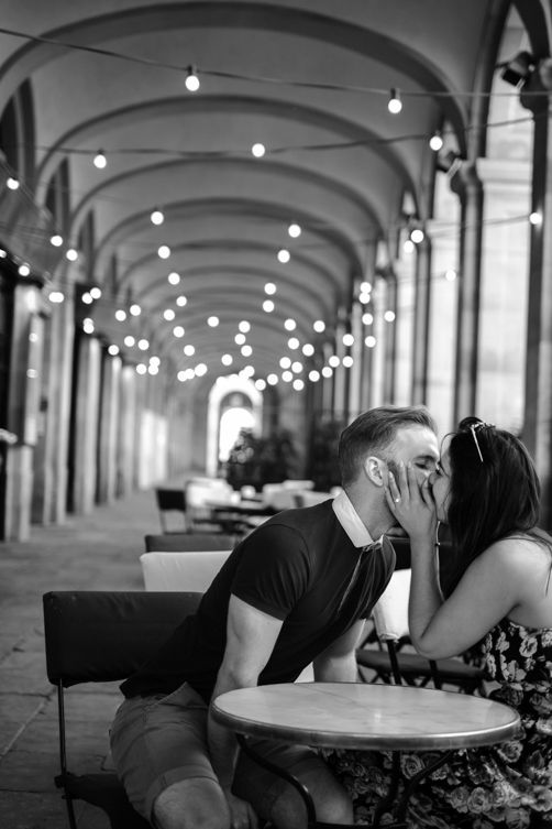 A couple kiss under the arches on their vacation photo shoot in Barcelona's old quarter.