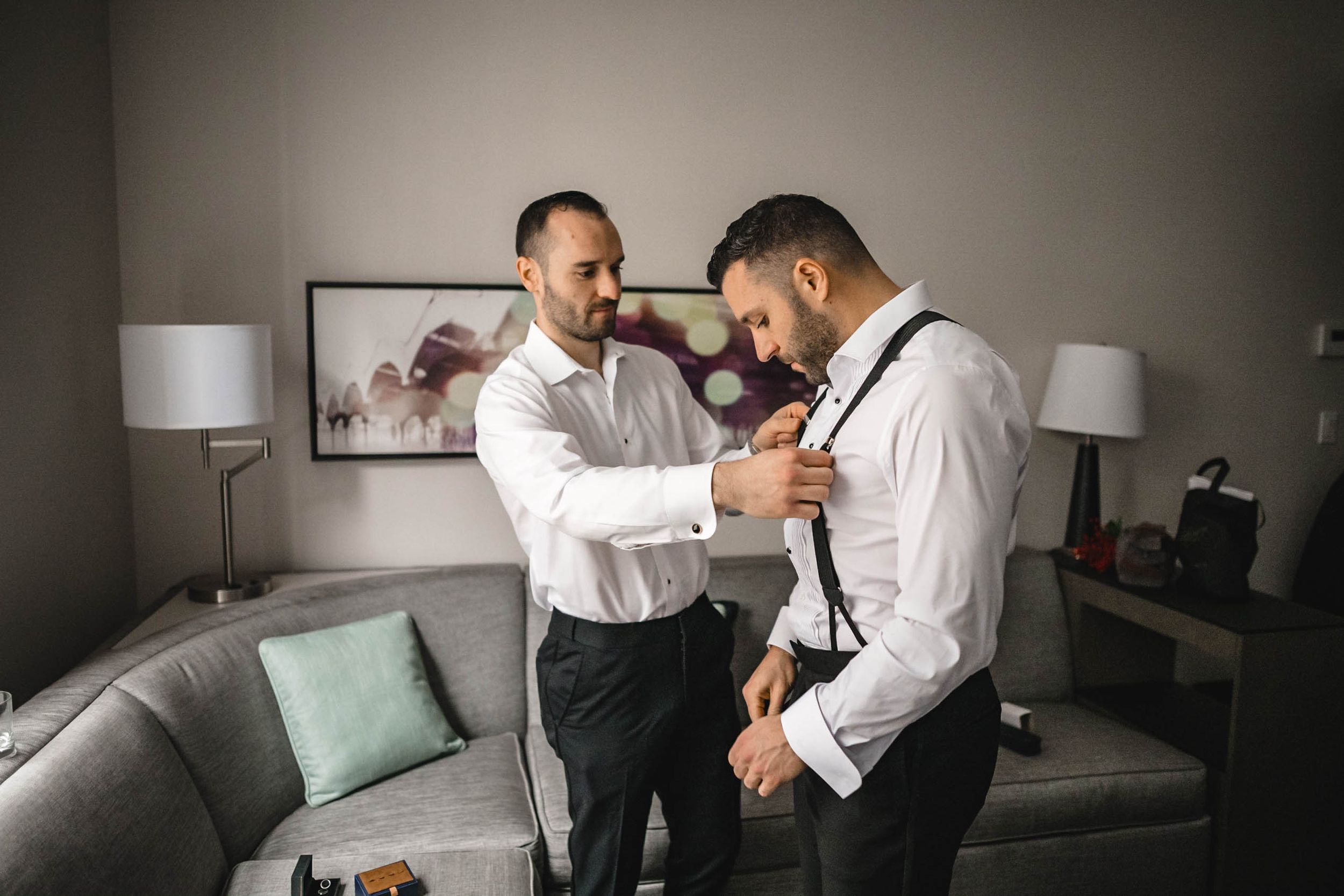 Men in formal white shirts preparing for a special occasion in an elegant setting.