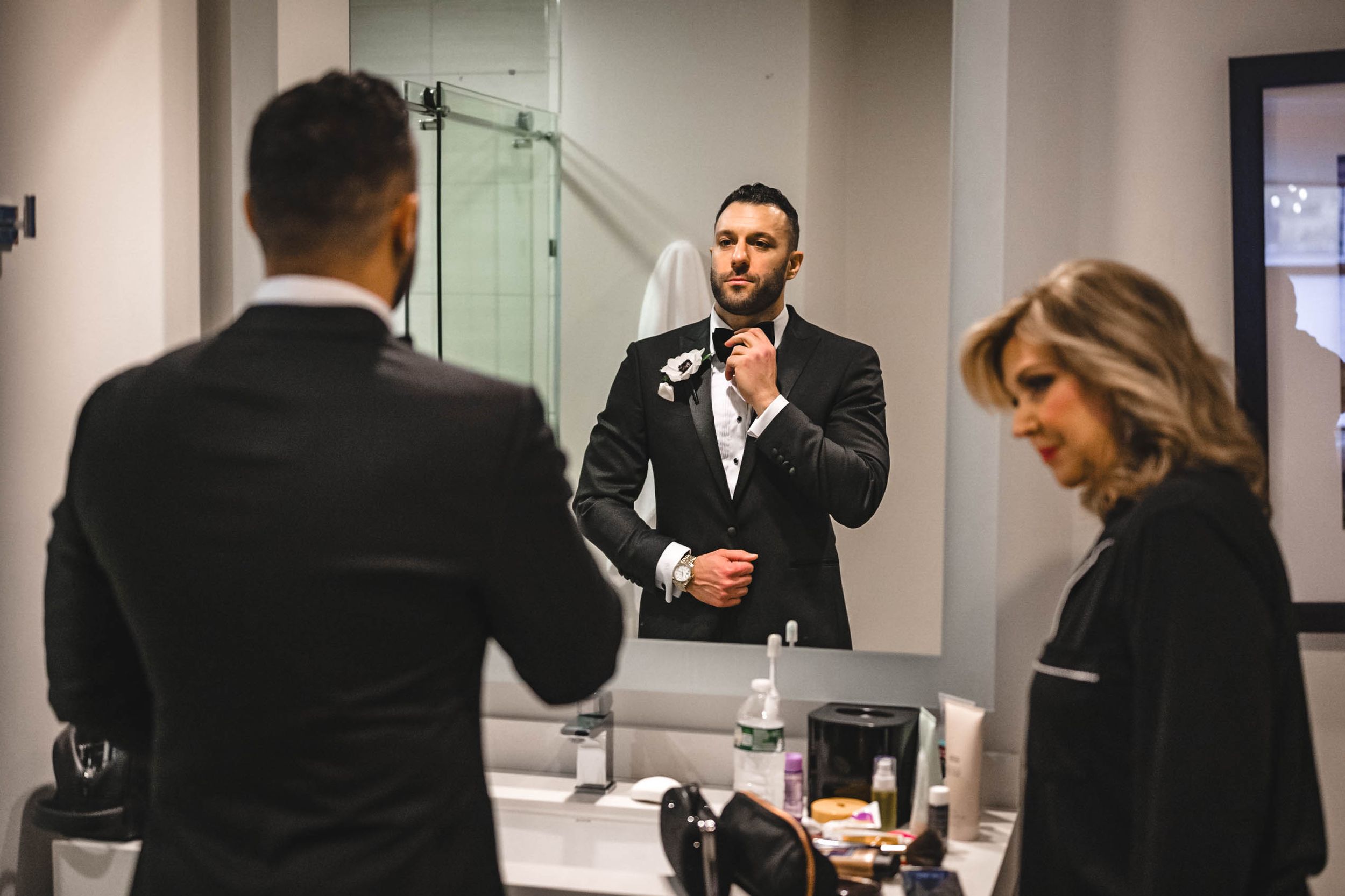 Groomsmen getting ready in a modern venue with glass walls and natural lighting.