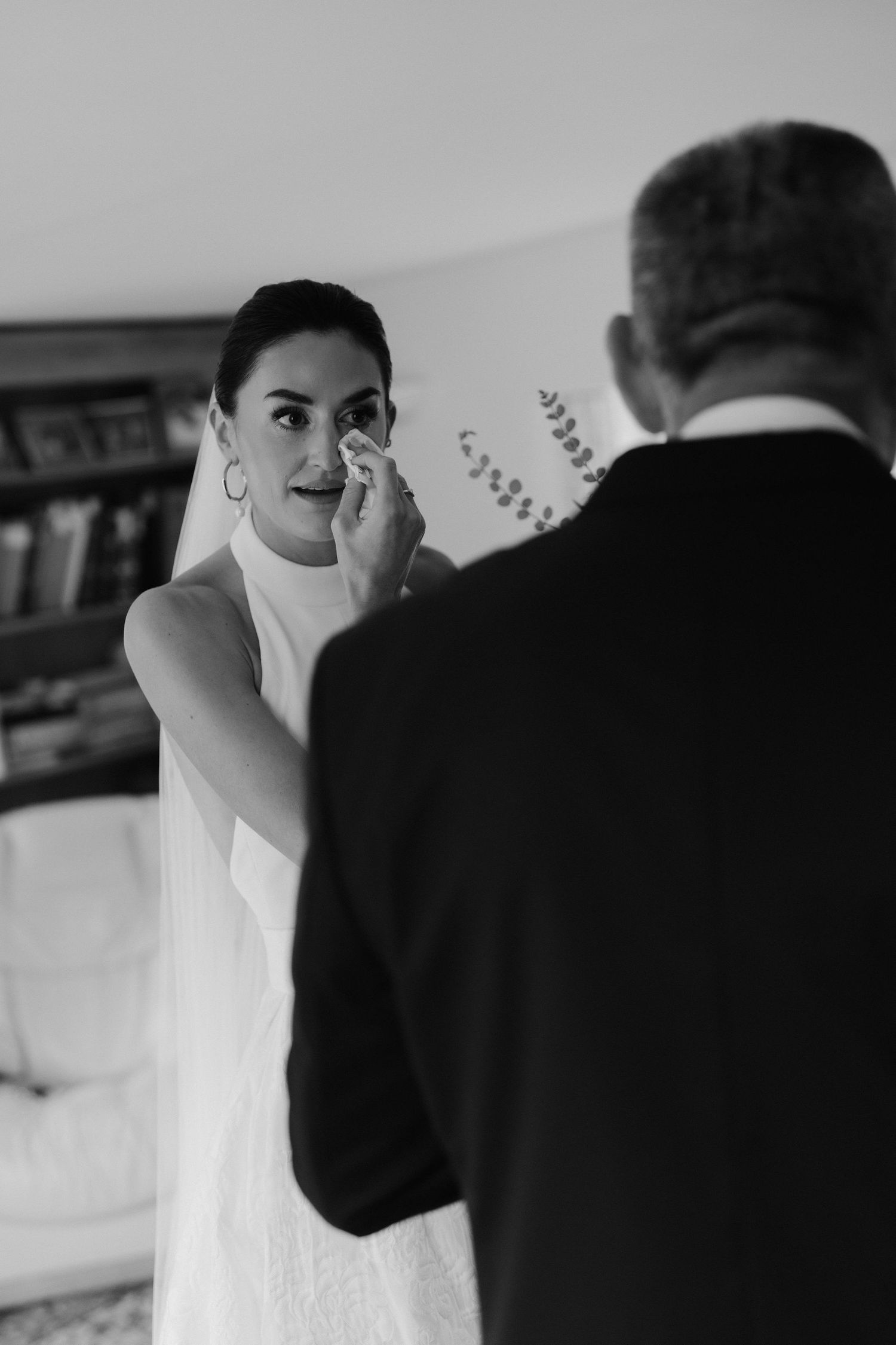 bride wiping tear away after seeing dad for the first time before her wedding ceremony in Oxfordshire