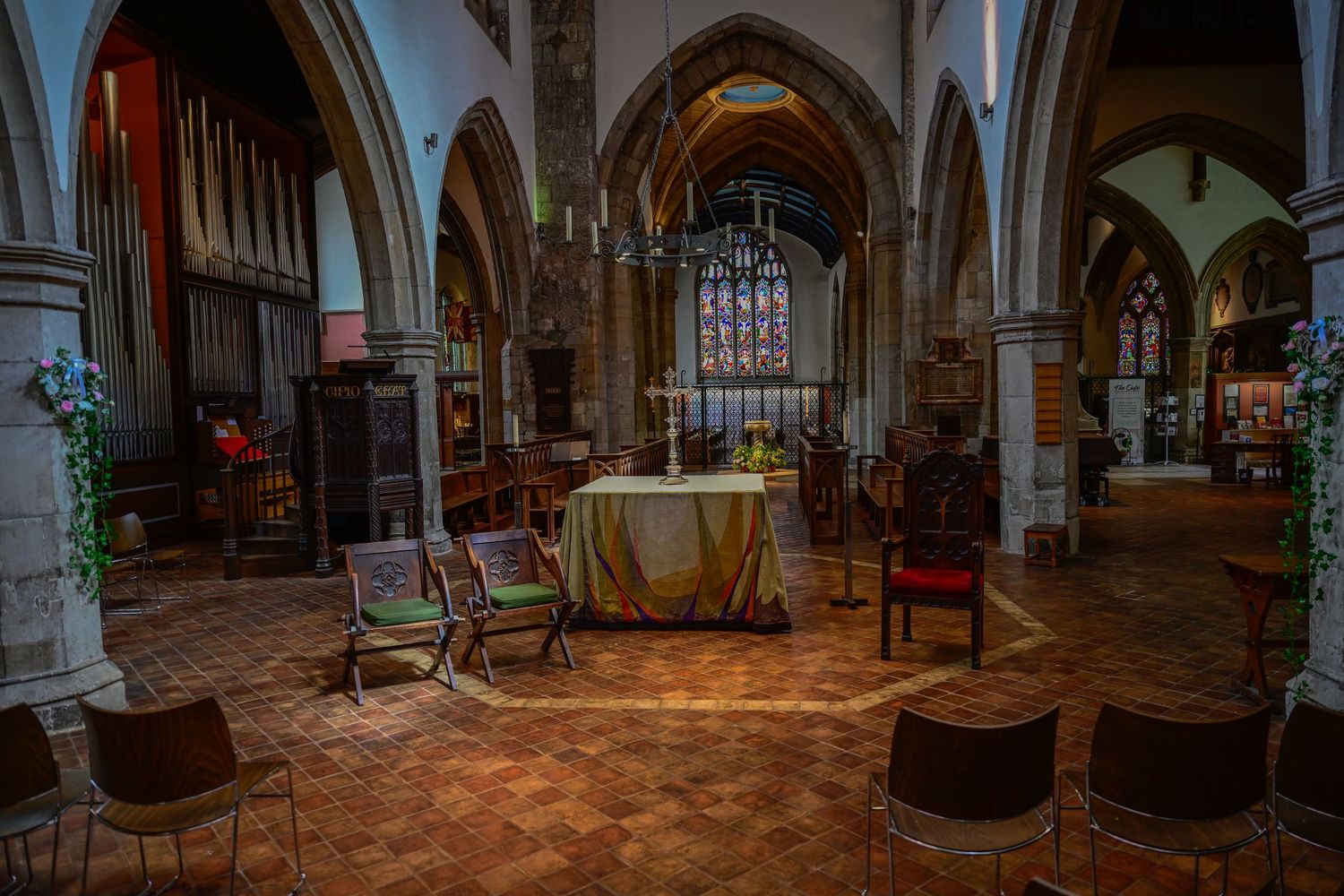 Interior view of a historic church sanctuary with stone arches, stained glass windows and wooden chairs.
