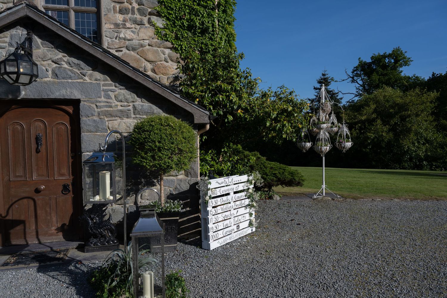 Stone cottage entrance with wooden door and white pallet decorations on gravel ground.