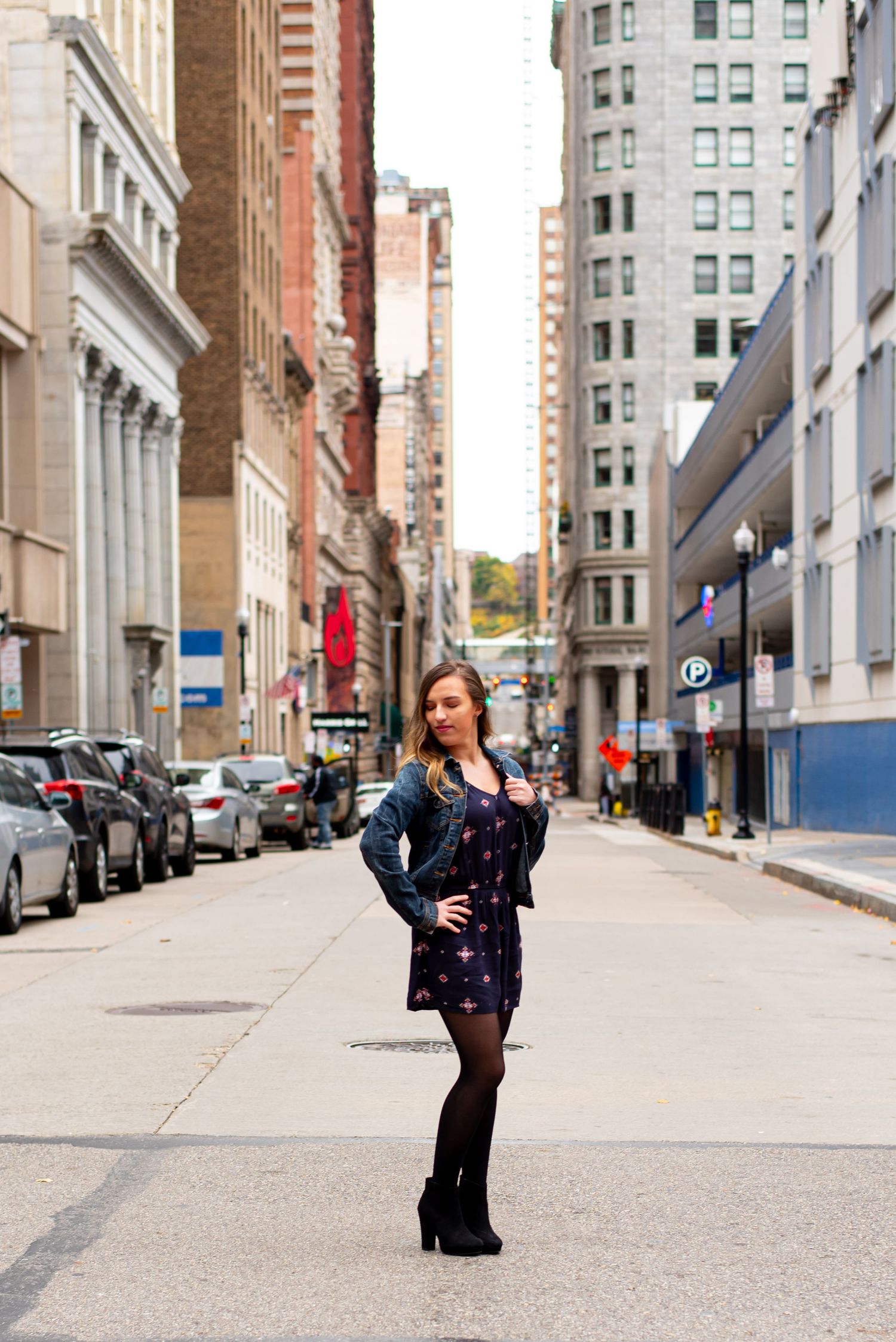 senior girl standing in downtown pittsburgh surrounded by tall buildings