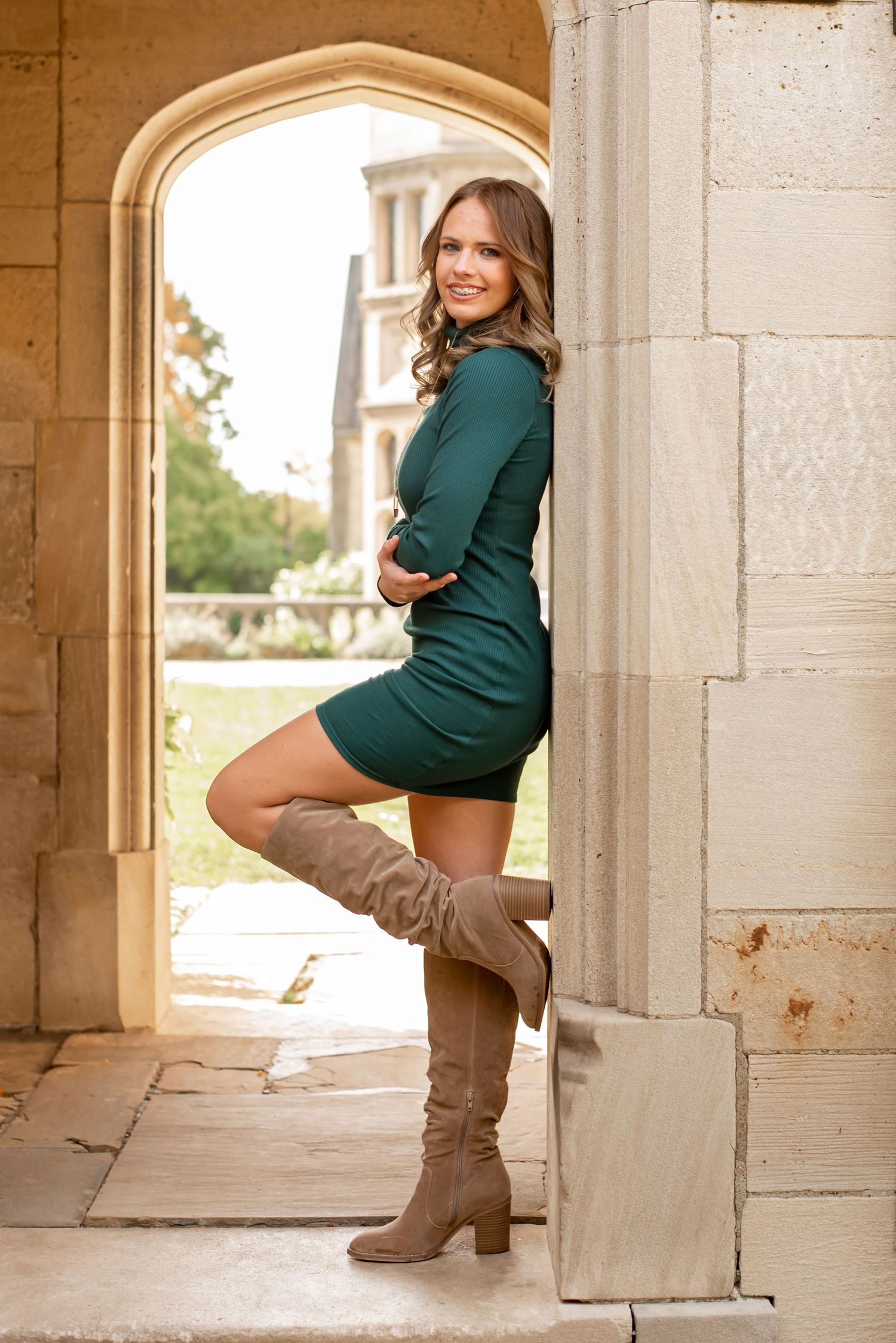 senior girl in a green dress in boots standing in arch at hartwood acres mansion