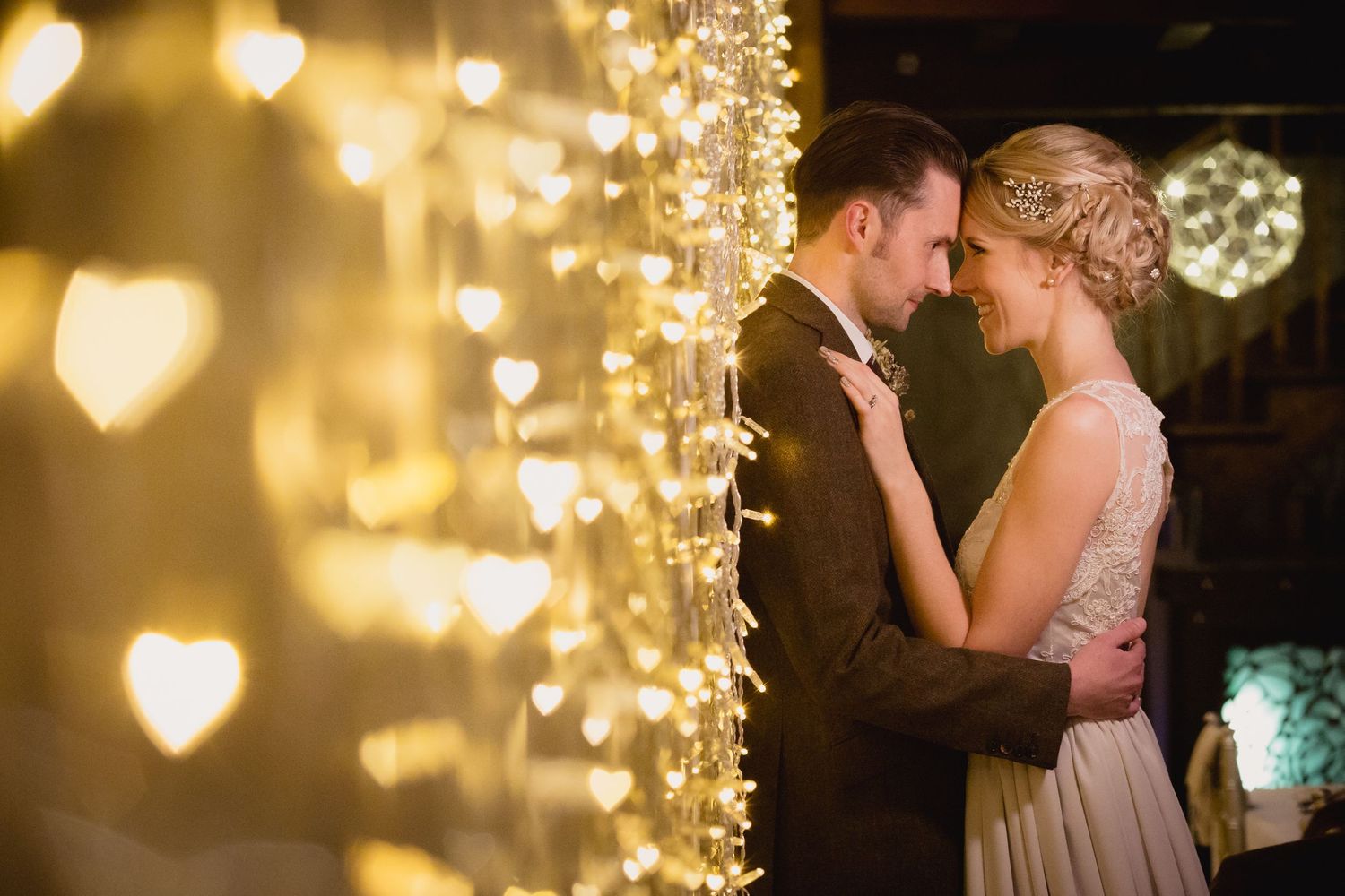 Romantic couples sharing intimate moments under warm glowing string lights at an evening celebration.