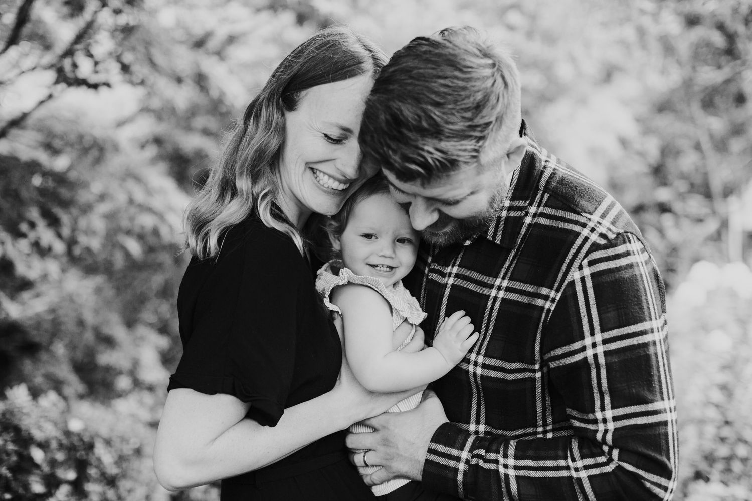 Black and white portrait of family sharing tender moment outdoors.