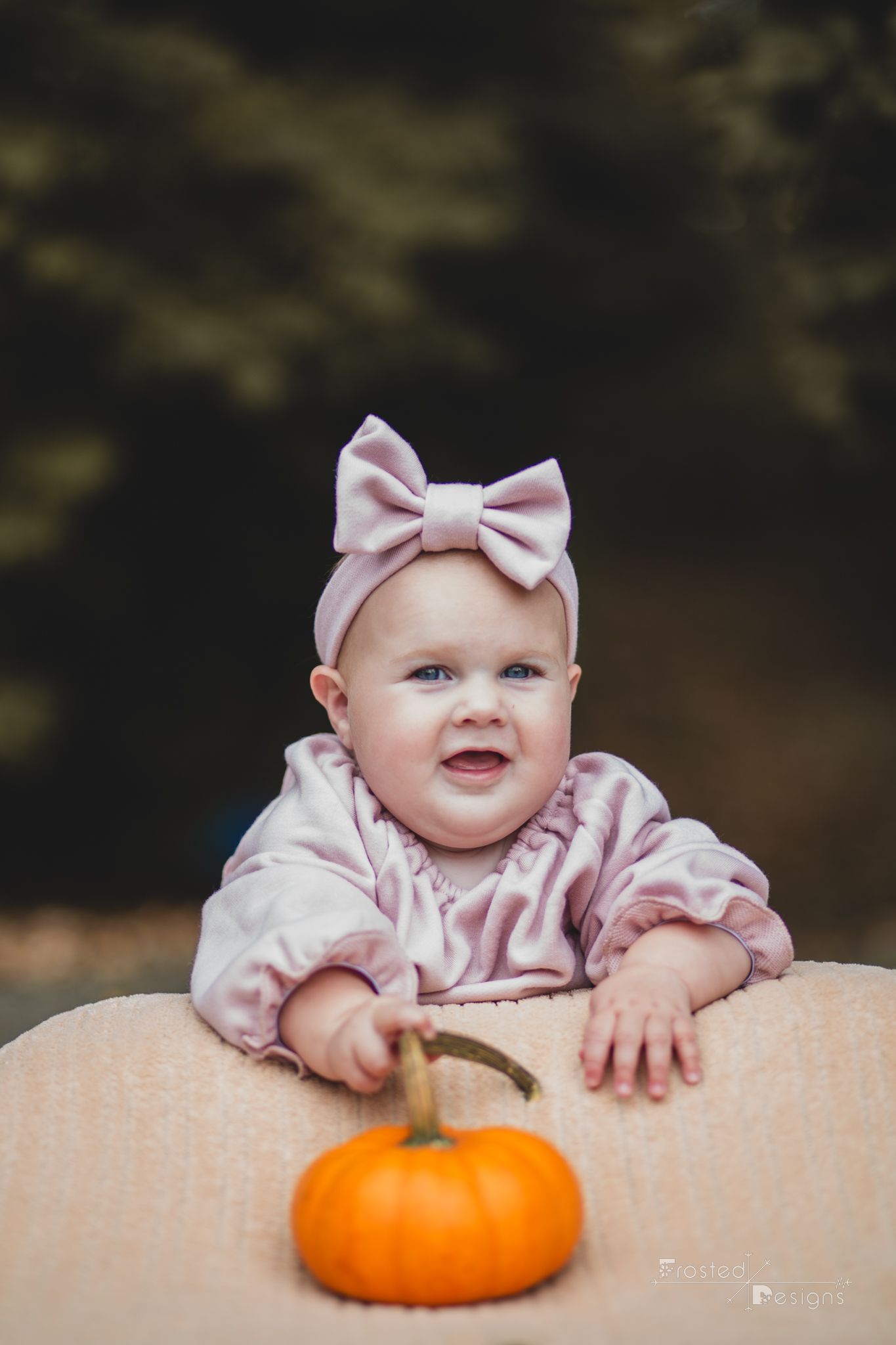6 month old girl in pink amongst fall foliage on a blanket.