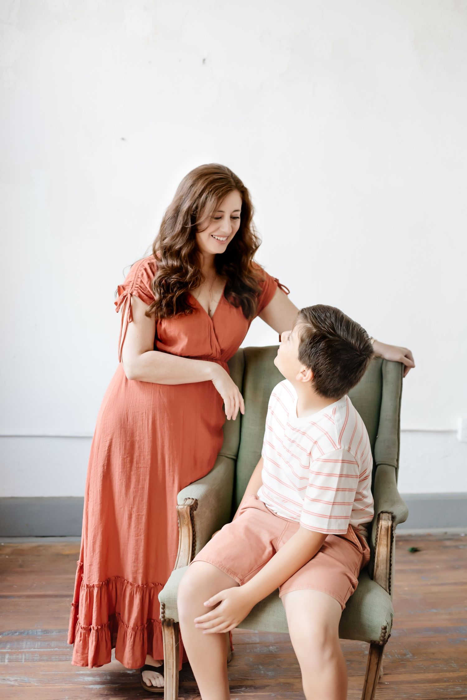 Mother and child sharing tender moment while sitting in green armchair.