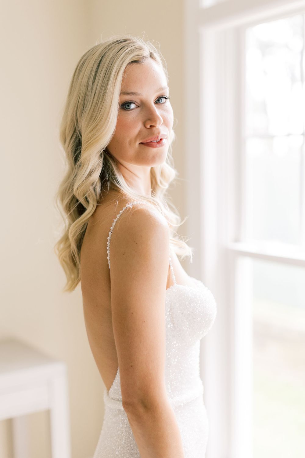 Classic bridal portrait in white dress with soft window lighting.