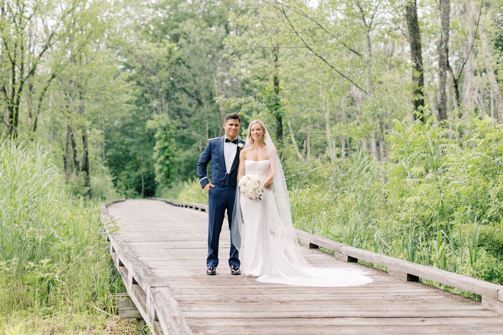 A couple walks along a wooden boardwalk surrounded by lush spring greenery.