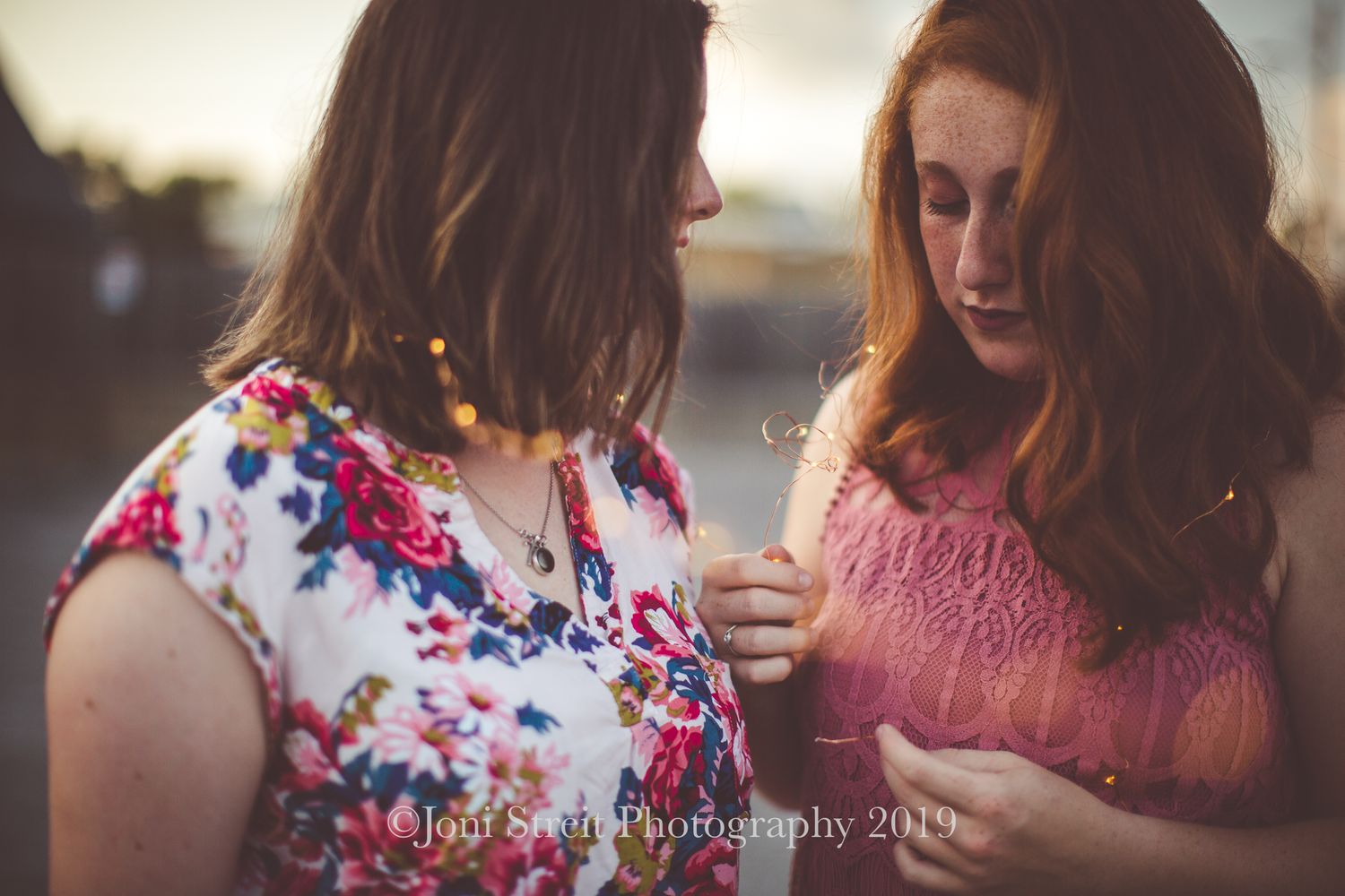 Two friends in summer outfits sharing a quiet moment at sunset.