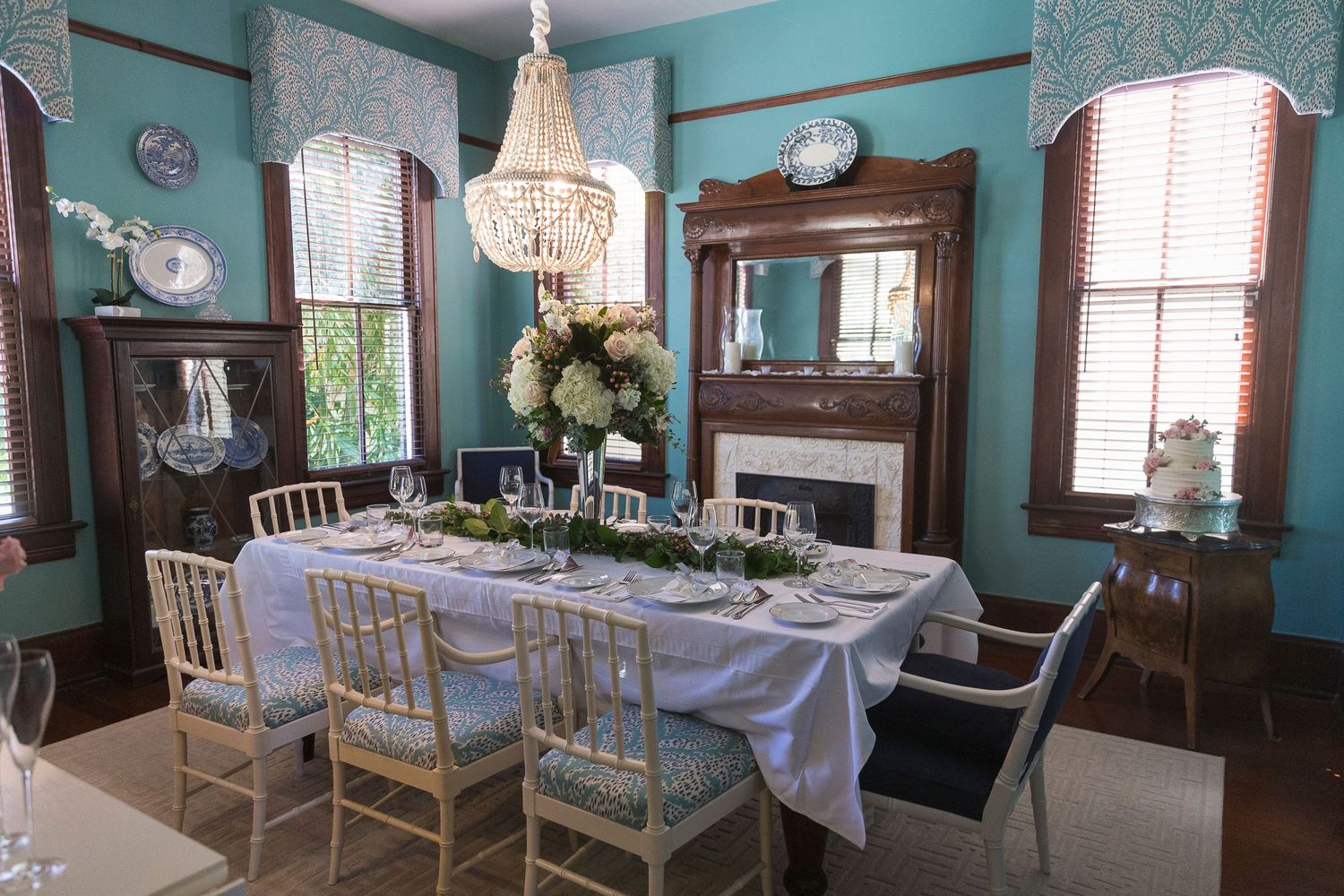 Elegant reception venue with turquoise walls, white chairs, and vintage decor creates a charming atmosphere.