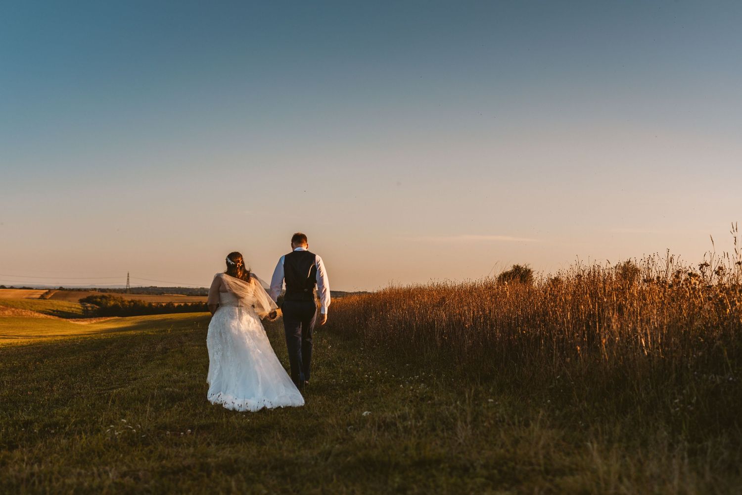 Bride and Groom walking in golden hour sunset Stone Barn The Cotswolds looks like film painting