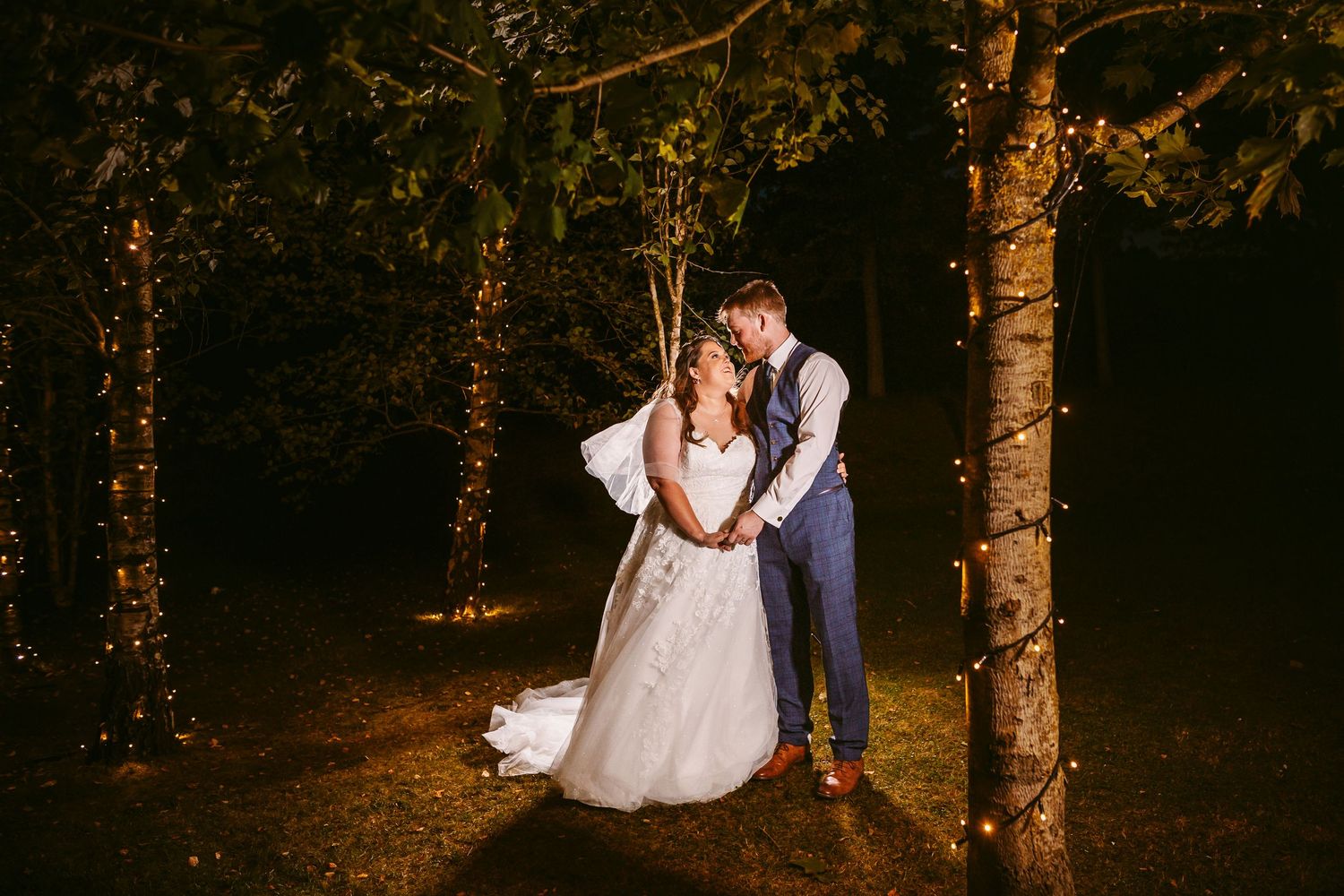 Bride and Groom Portrait in garden at night with pretty lights in trees Stone Barn The Cotswolds