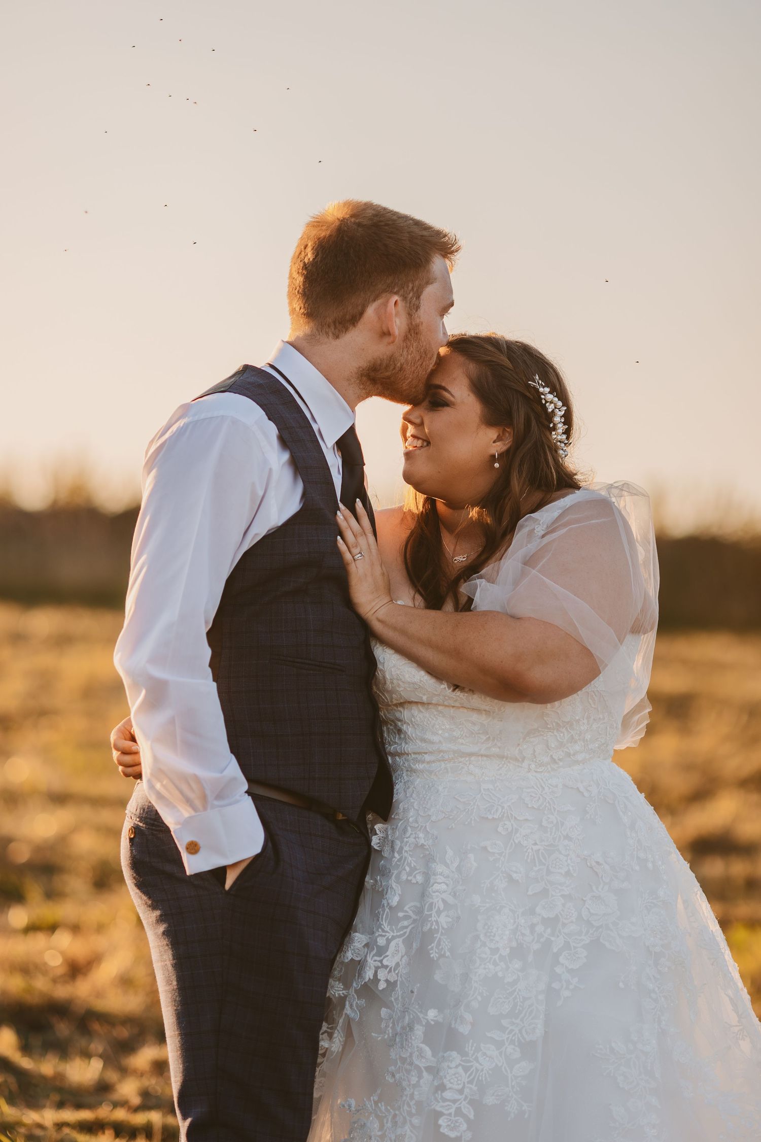 Groom kissing bride in golden hour sunset Stone Barn The Cotswolds