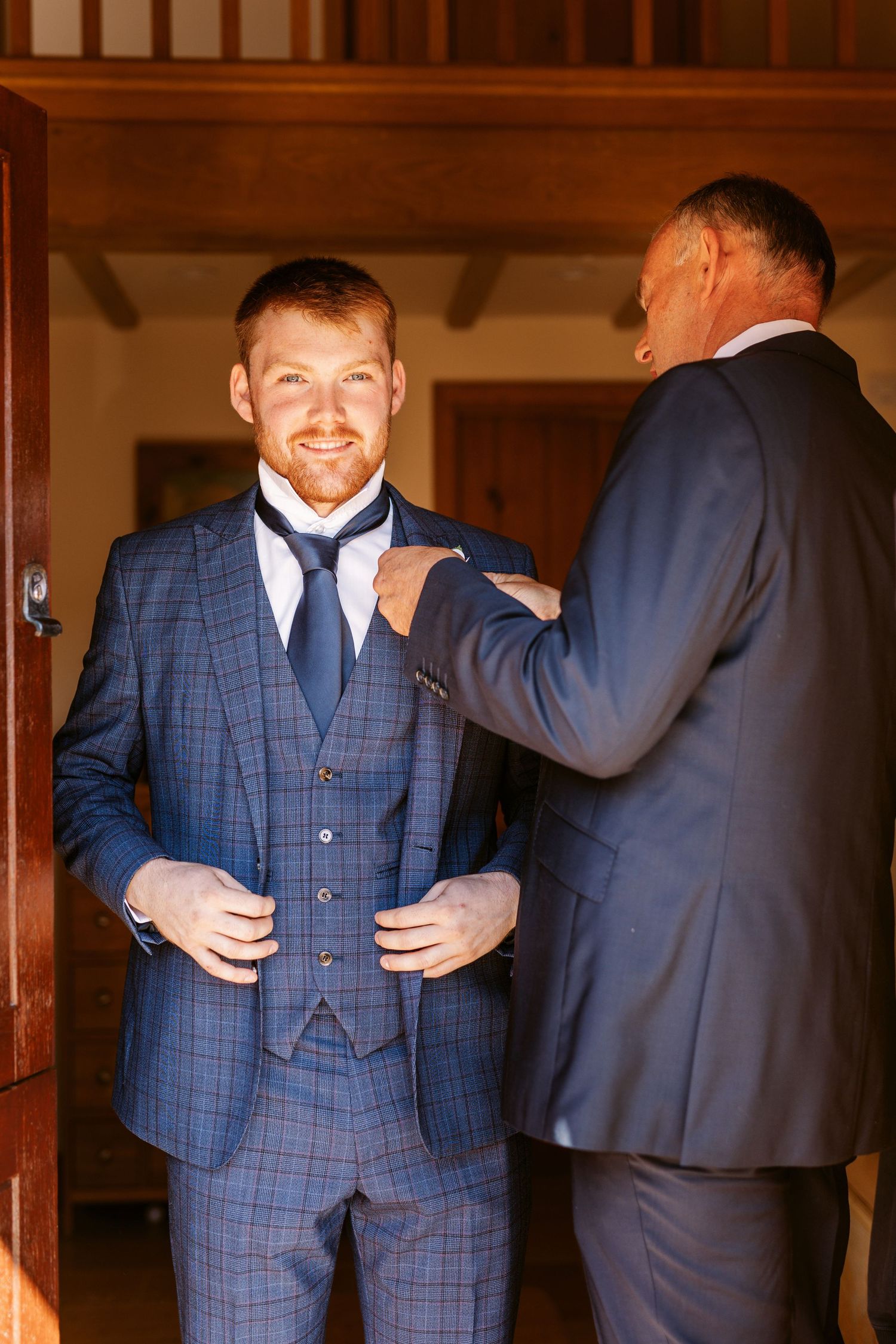 Grooms dad helping him with his button hole