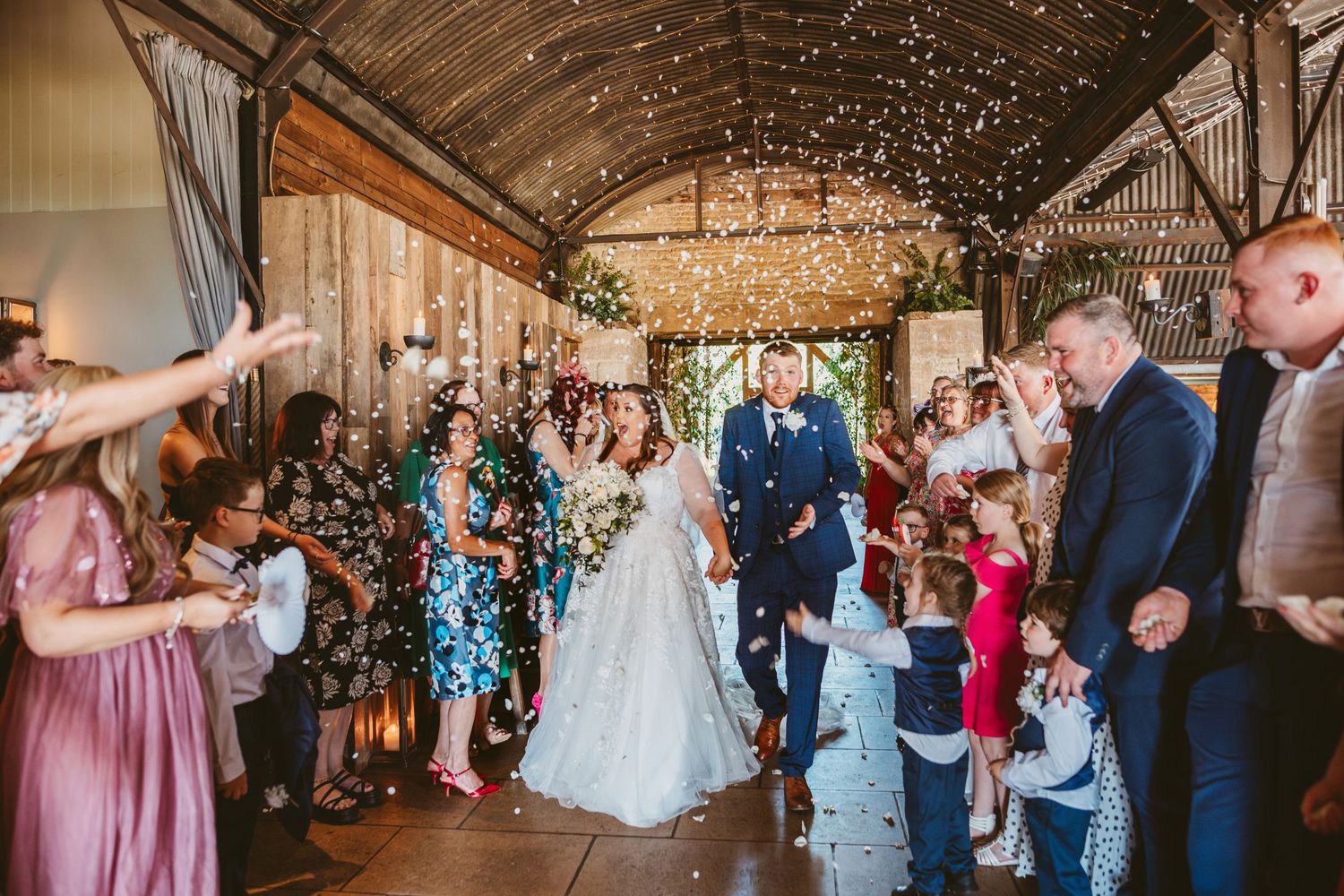 Bride and Groom leaving the ceremony with confetti thrown over them Stone Barn Wedding Venue Cheltenham The Cotswolds