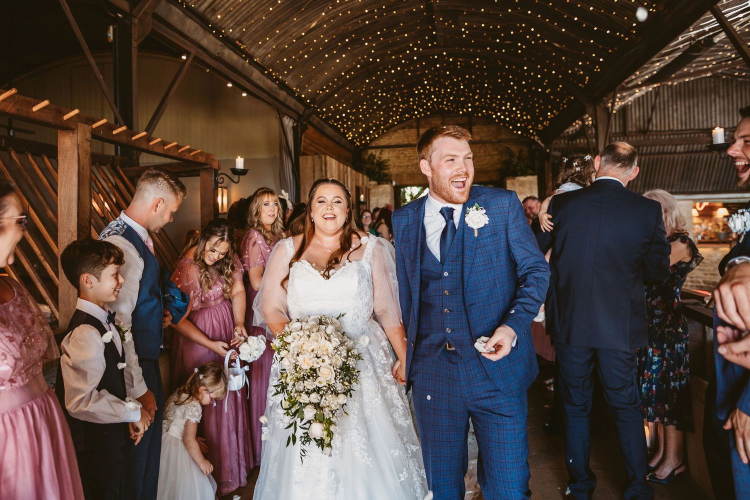 Bride and Groom leaving the ceremony with confetti thrown over them Stone Barn Wedding Venue Cheltenham The Cotswolds